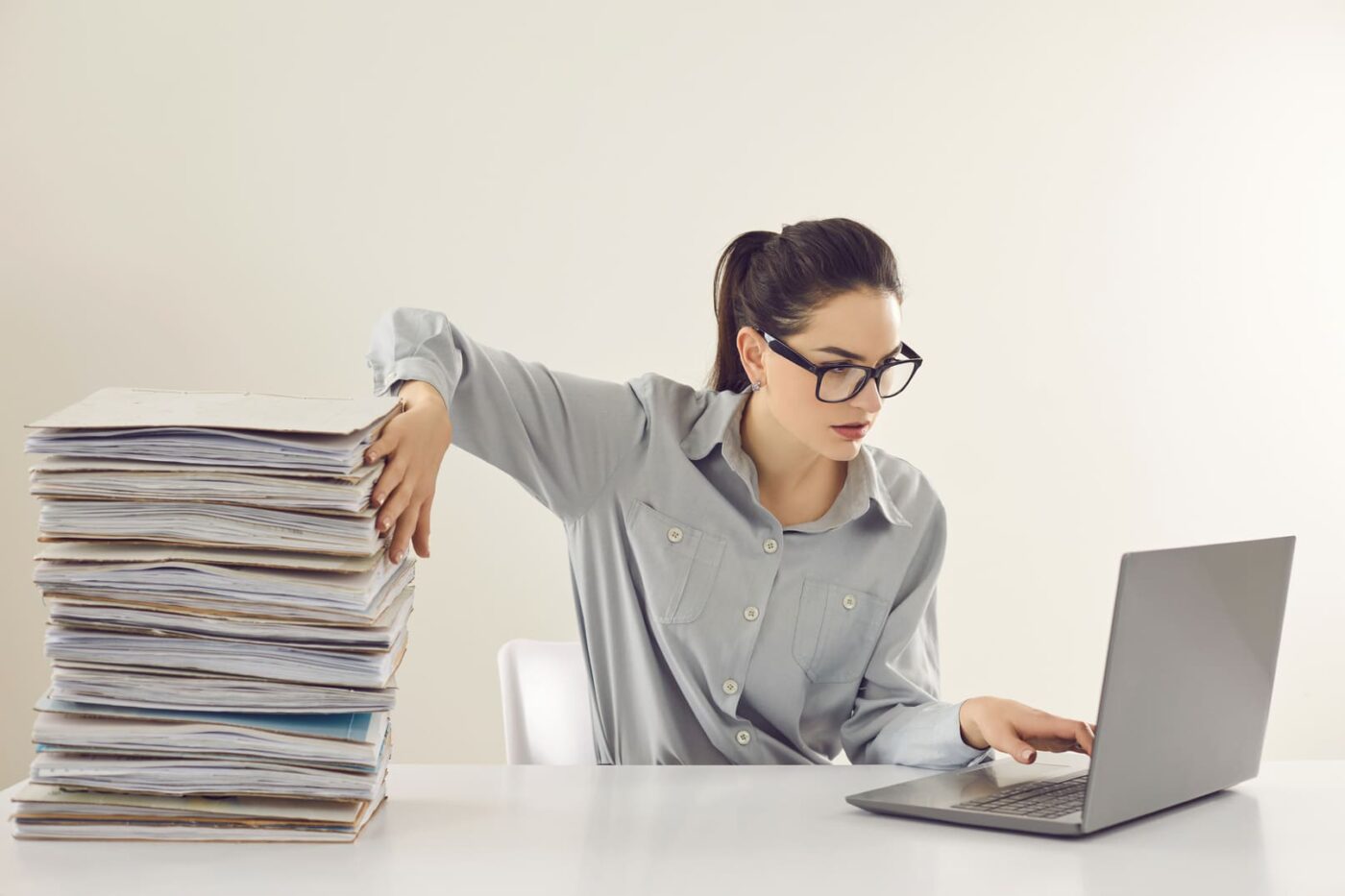 femme devant un ordinateur et une pile de documents
